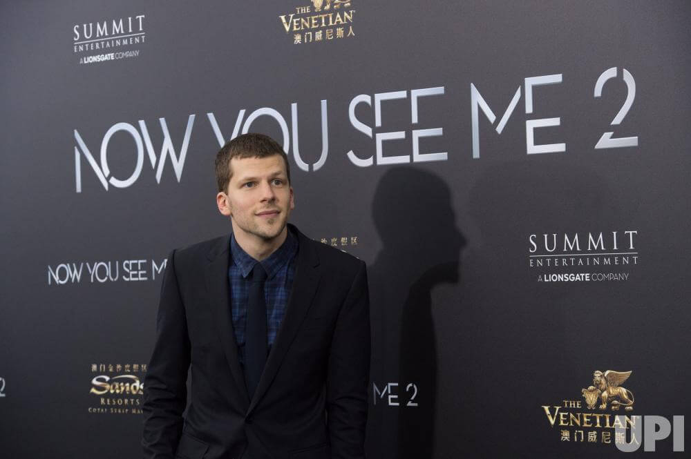Jesse Eisenberg mengenakan jas hitam berpose di sebuah premiere film Now You See Me 2